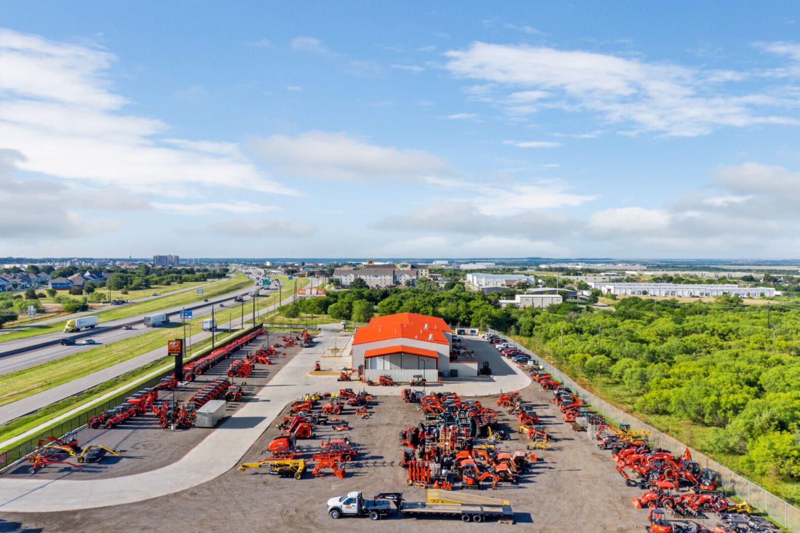 Red heavy equipment vehicles in the parking lot of a warehouse with an orange roof