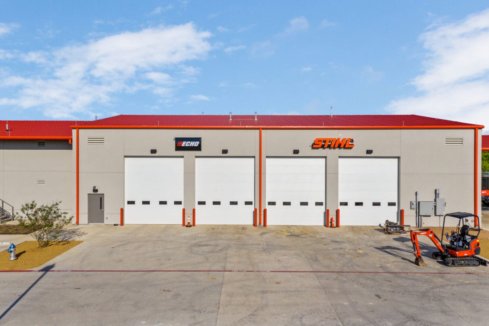 Four garage doors on a gray warehouse with an orange roof